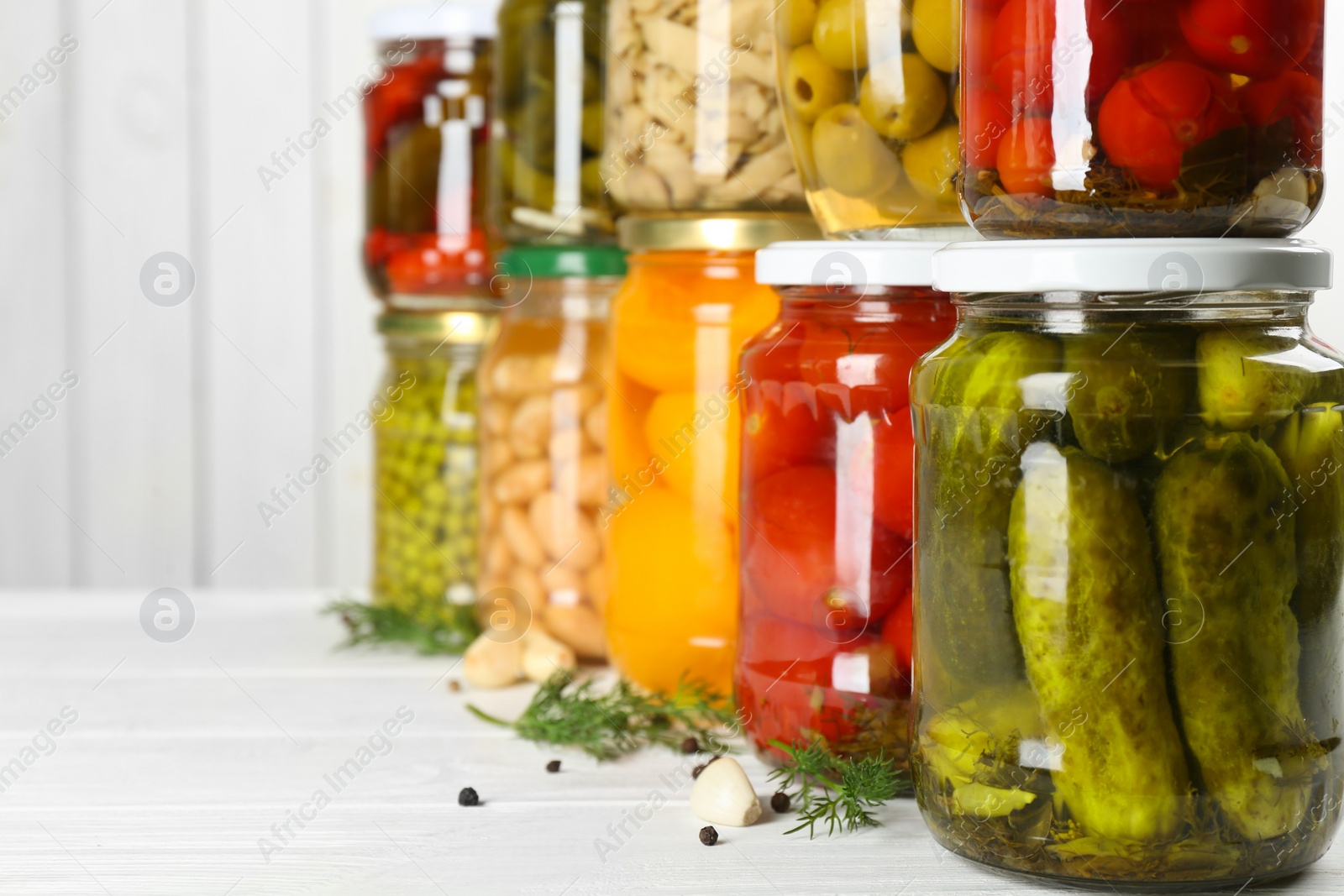 Photo of Glass jars with different pickled foods on white wooden background, closeup