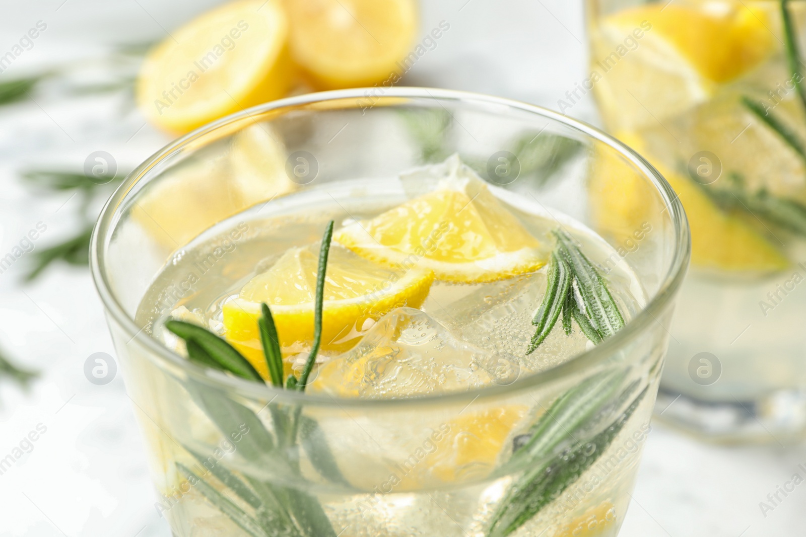 Photo of Glass of refreshing lemonade with rosemary on table, closeup. Summer drink