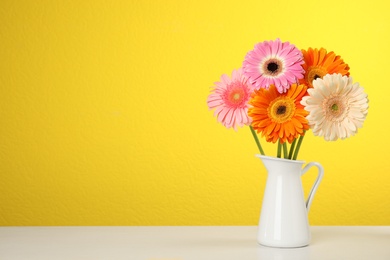 Photo of Bouquet of beautiful bright gerbera flowers in vase on table against color background. Space for text