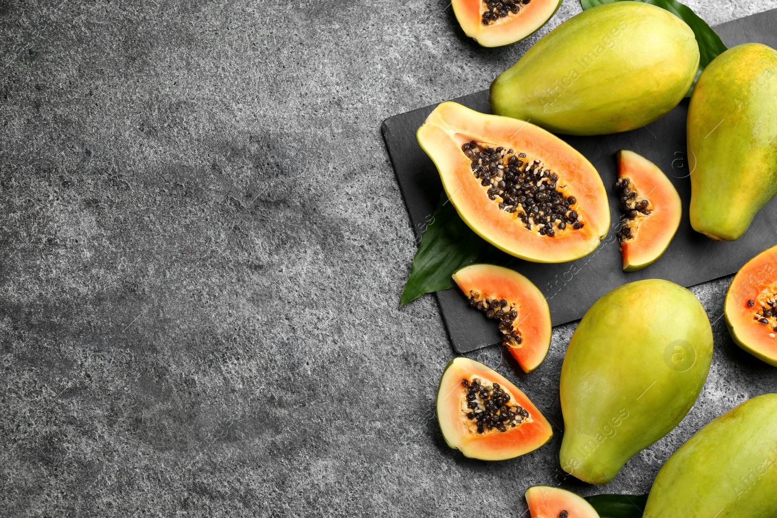 Photo of Fresh ripe papaya fruits on grey table, flat lay. Space for text