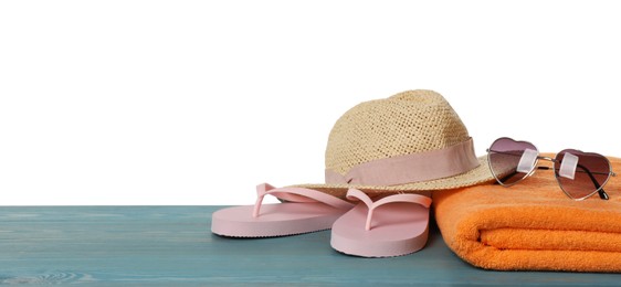 Photo of Beach towel, flip flops, straw hat and heart shaped sunglasses on light blue wooden surface against white background. Space for text