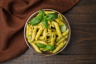 Photo of Delicious pasta with pesto sauce and basil on wooden table, top view