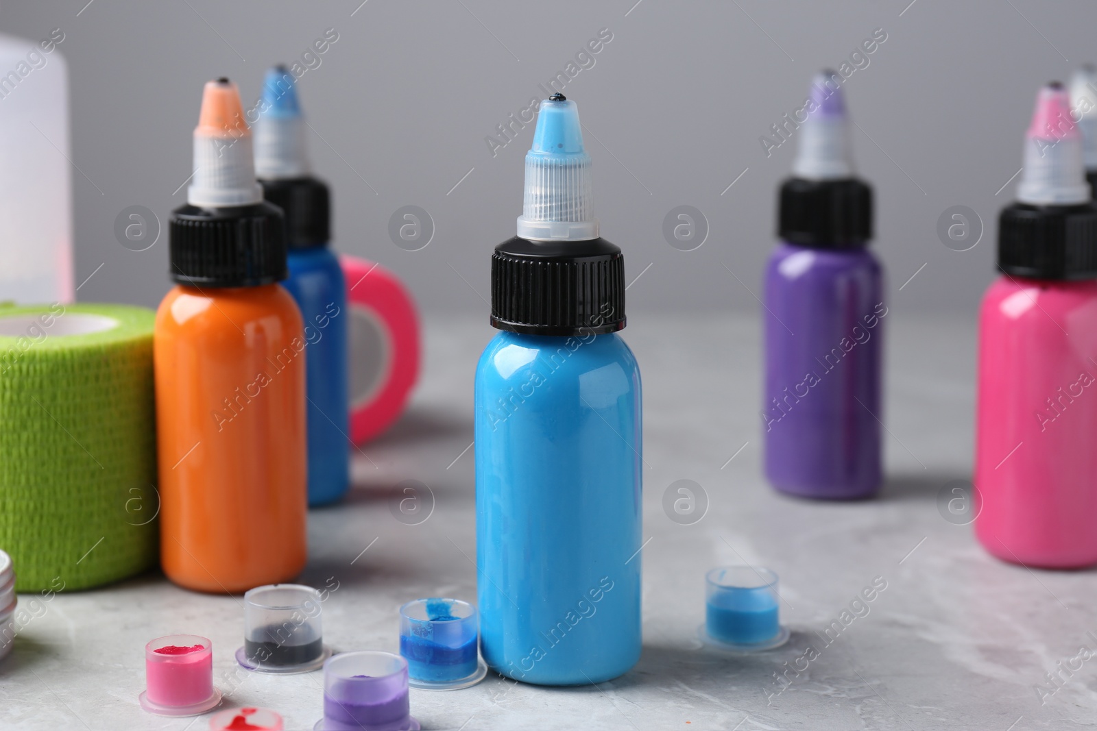 Photo of Colorful tattoo inks on light grey table, closeup