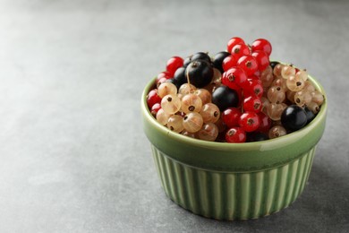 Different fresh ripe currants in bowl on light grey table, closeup. Space for text