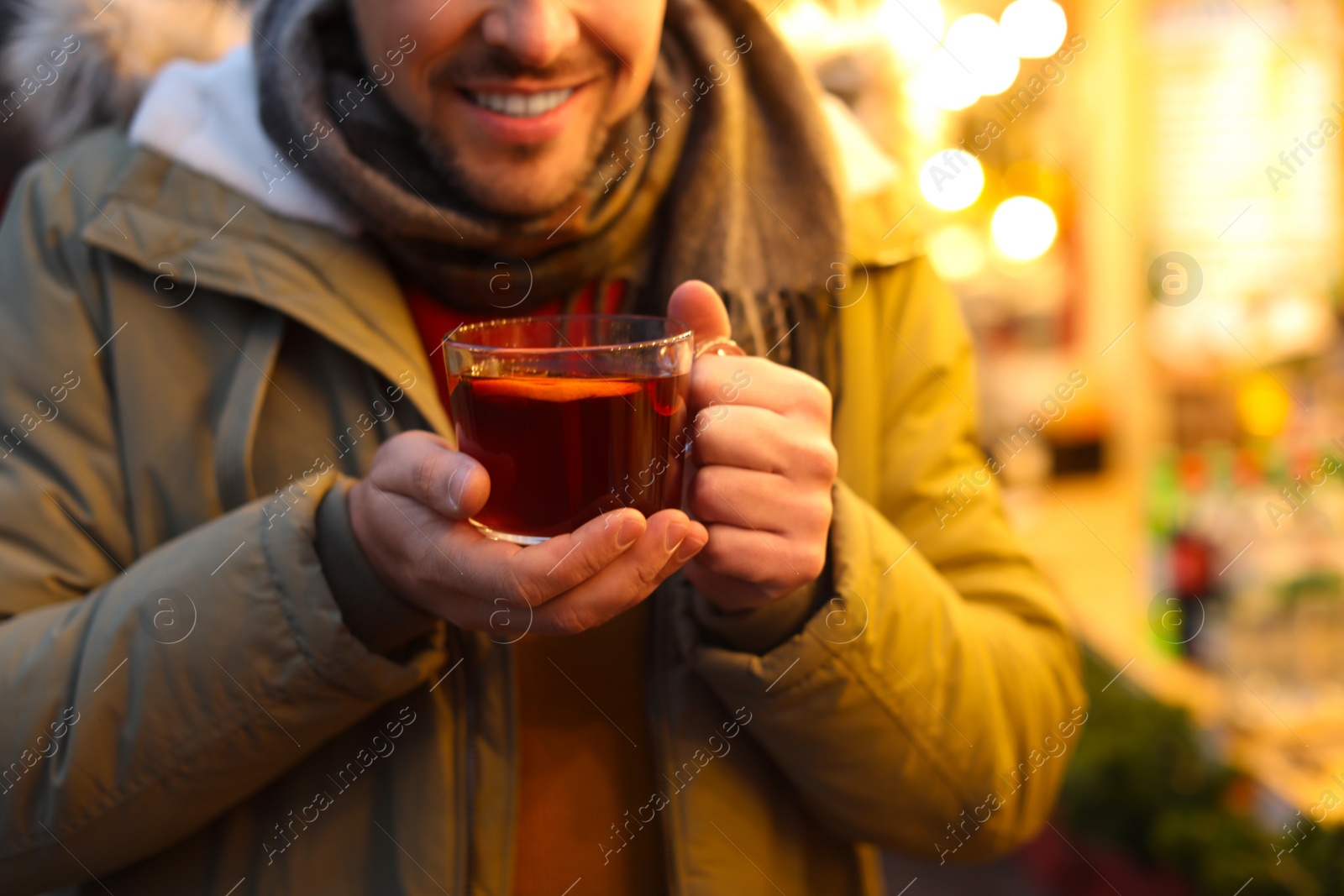 Photo of Happy man with mulled wine at winter fair, closeup