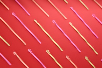 Photo of Colorful plastic drinking straws on red background, flat lay