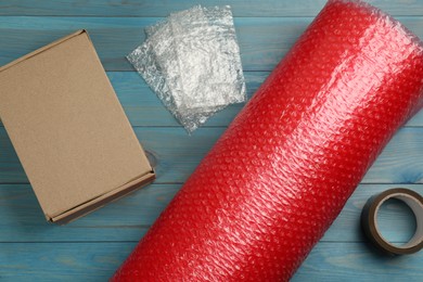 Photo of Flat lay composition with bubble wrap roll on light blue background