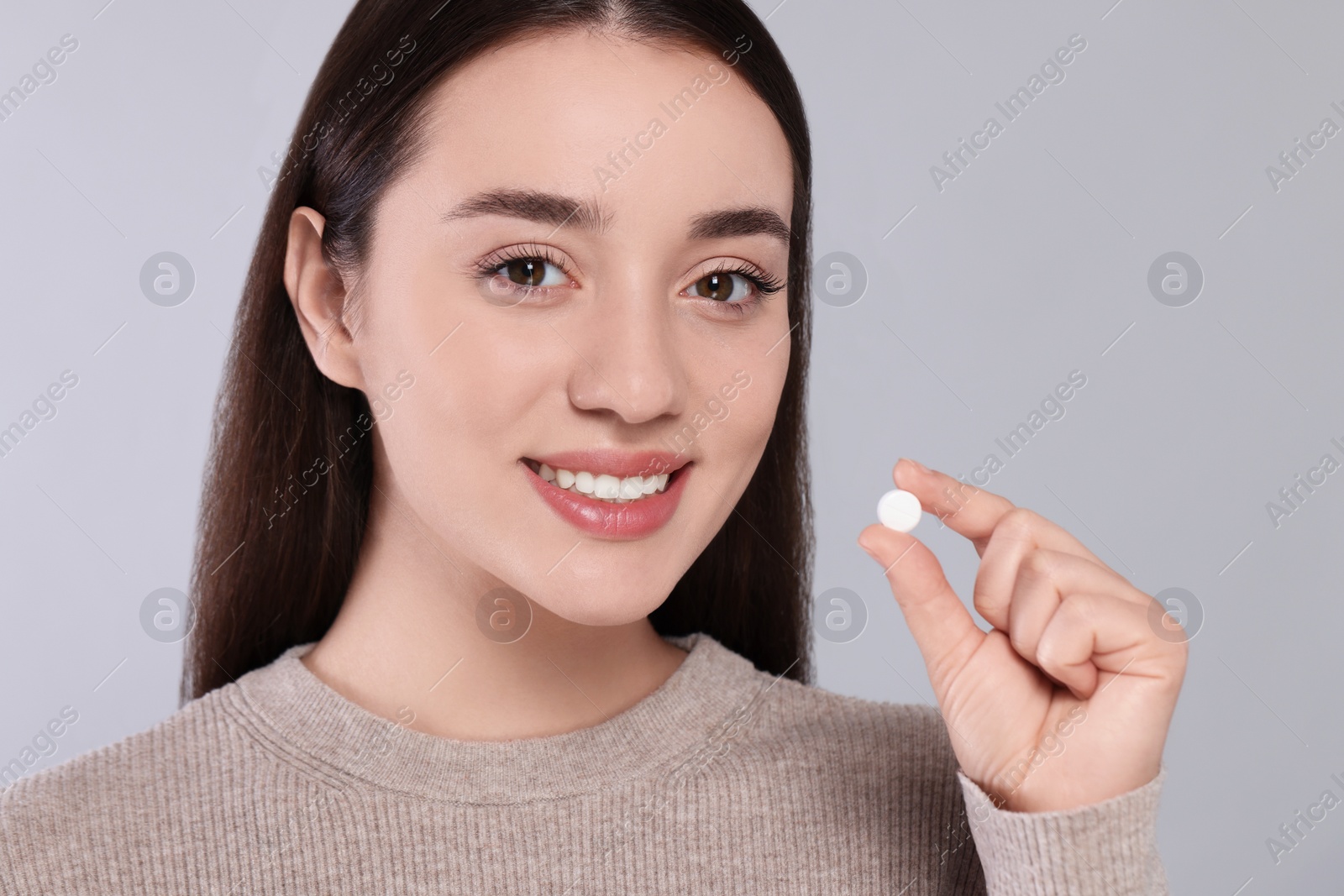 Photo of Happy woman with pill on gray background