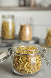 Glass jar of sprouted green buckwheat on light grey table