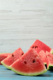 Photo of Slices of tasty ripe watermelon on turquoise wooden table, space for text