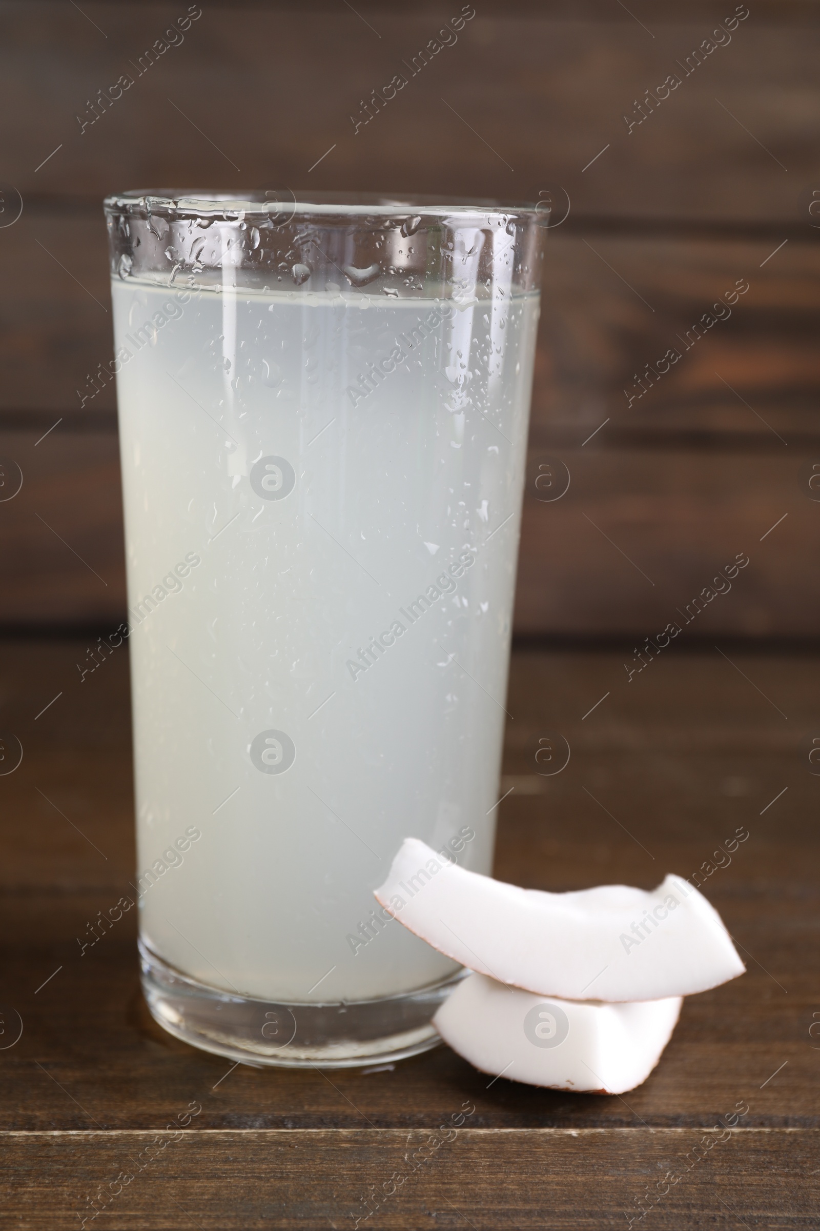 Photo of Glass of coconut water and nut on wooden table