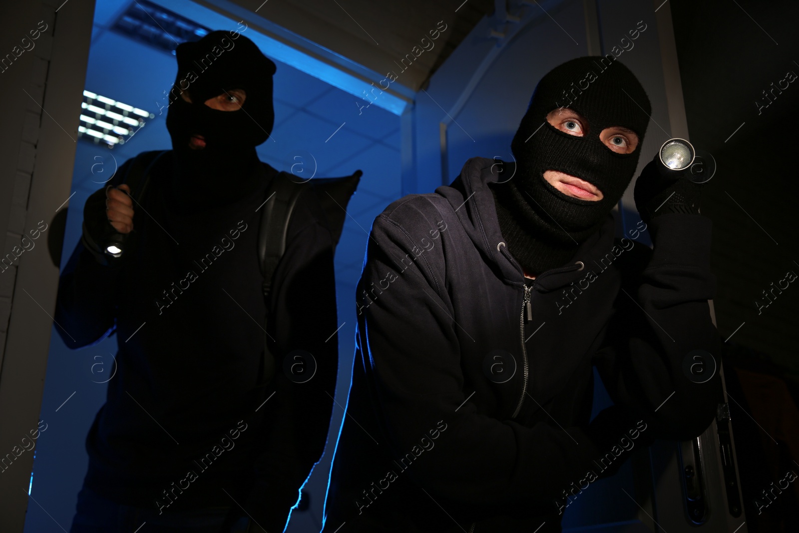 Photo of Thieves with flashlights breaking into house at night