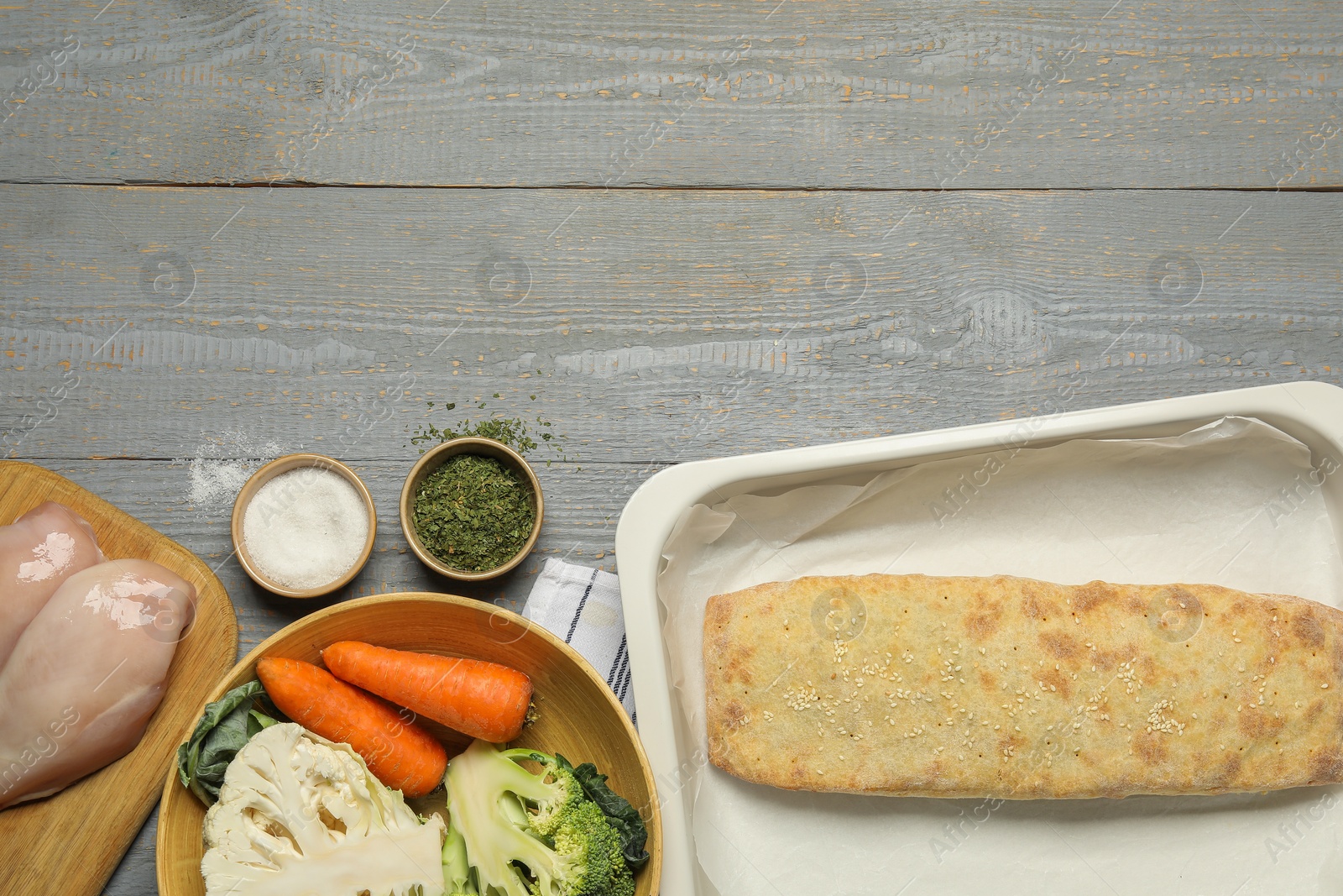 Photo of Delicious strudel with chicken and vegetables on grey wooden table, flat lay. Space for text