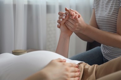 Photo of Doula taking care of pregnant woman indoors, closeup. Preparation for child birth