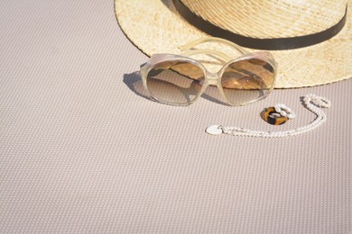 Photo of Stylish hat, sunglasses and jewelry on grey surface, space for text