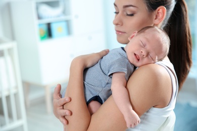 Young woman with her newborn baby at home. Space for text