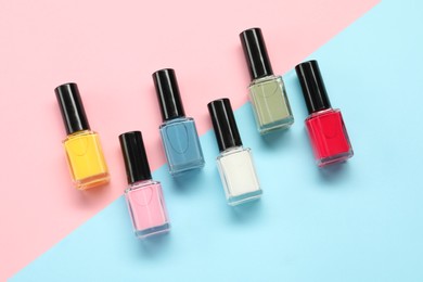 Bright nail polishes in bottles on color background, flat lay