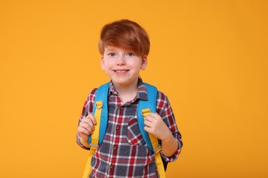 Photo of Portrait of happy schoolboy on orange background