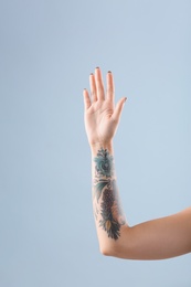 Female arm with tattoo on color background