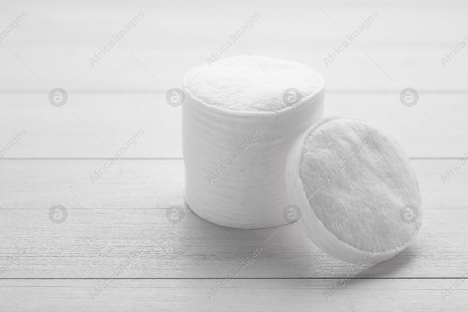 Photo of Stack of clean cotton pads on white wooden table, closeup. Space for text