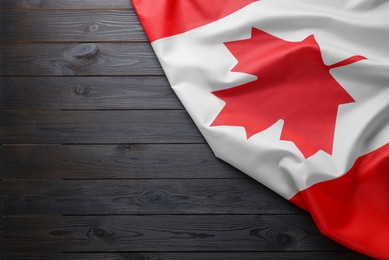 Photo of Flag of Canada on dark wooden table, top view. Space for text