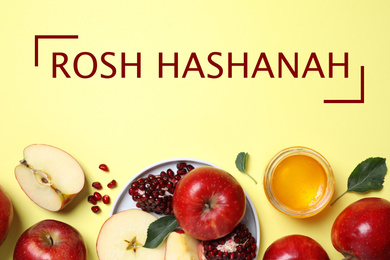 Honey, apples and pomegranate on yellow background, flat lay. Rosh Hashanah holiday