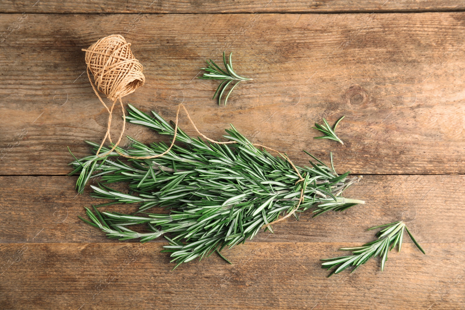 Photo of Fresh rosemary branches and twine on wooden table, top view