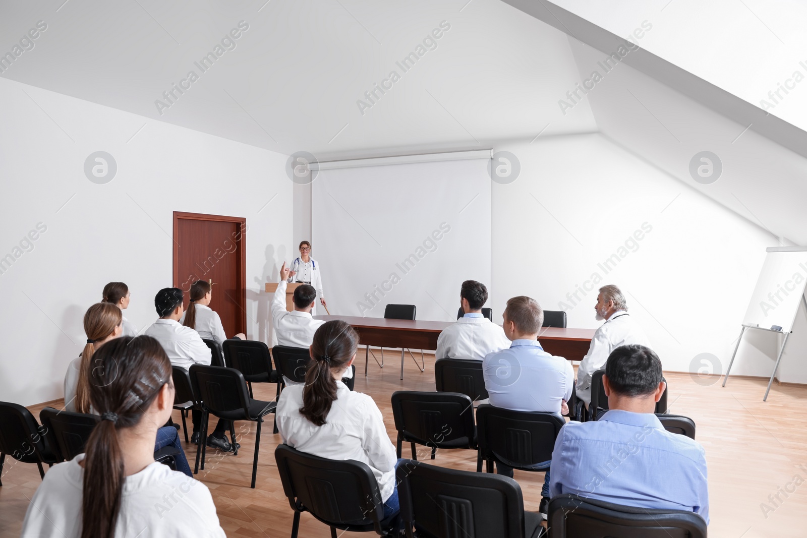 Photo of Doctor giving lecture in conference room with projection screen