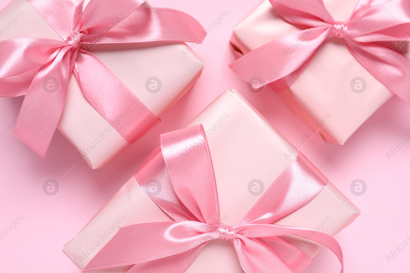 Photo of Beautiful gift boxes on pink background, flat lay