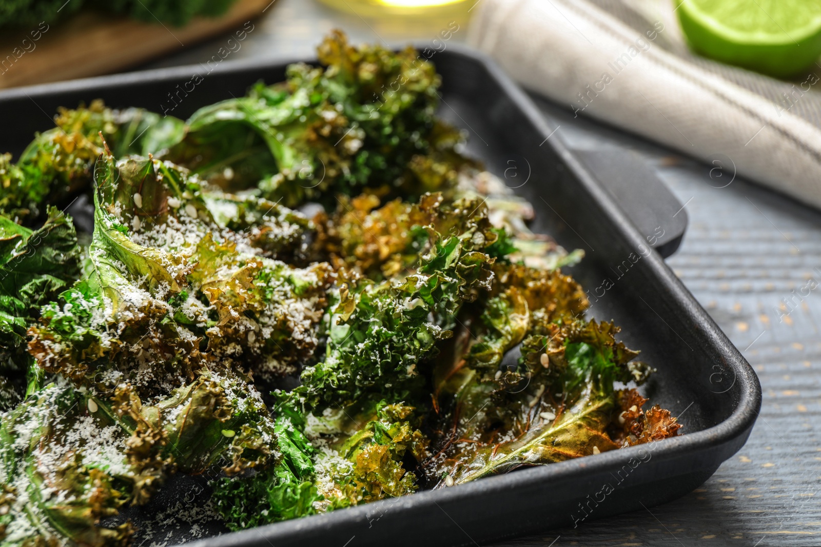 Photo of Tasty baked kale chips on grey table, closeup