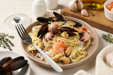 Photo of Delicious pasta with sea food served on white wooden table