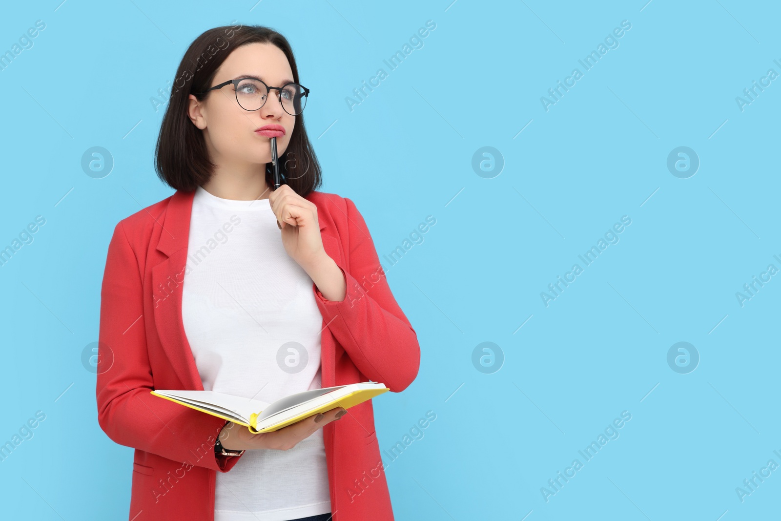 Photo of Young intern with notebook and pen on light blue background. Space for text