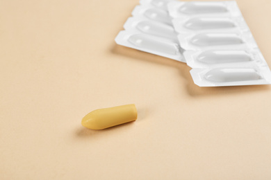 Photo of Suppositories on beige background, closeup view. Hemorrhoid treatment