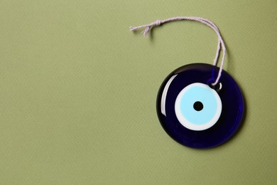 Photo of Evil eye amulet on olive background, top view. Space for text