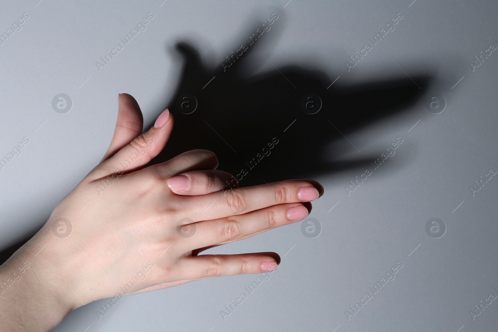 Photo of Shadow puppet. Woman making hand gesture like dog on grey background, closeup