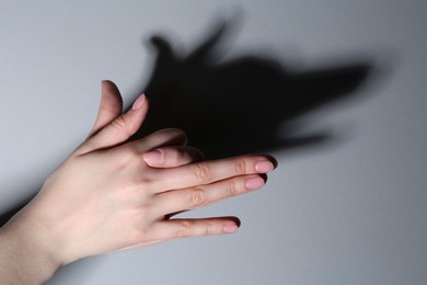 Photo of Shadow puppet. Woman making hand gesture like dog on grey background, closeup