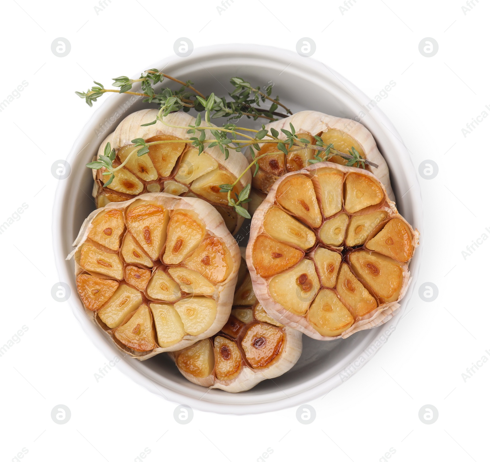 Photo of Heads of fried garlic and thyme in bowl isolated on white, top view