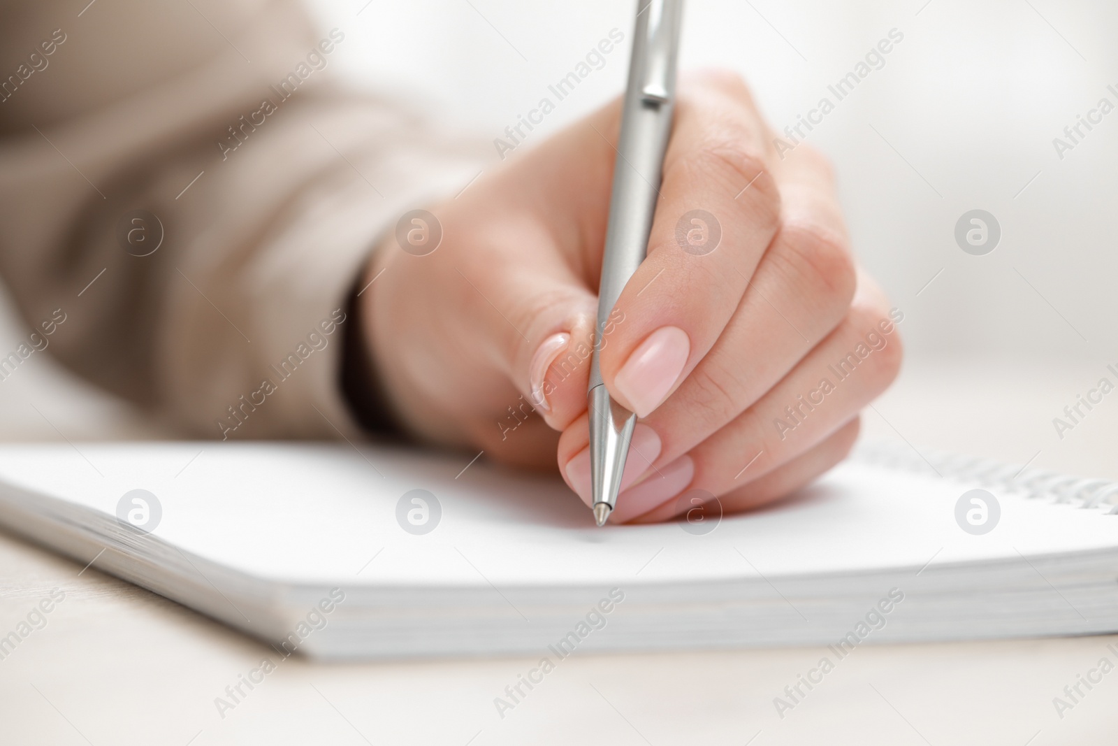 Photo of Woman writing in notebook at light table, closeup