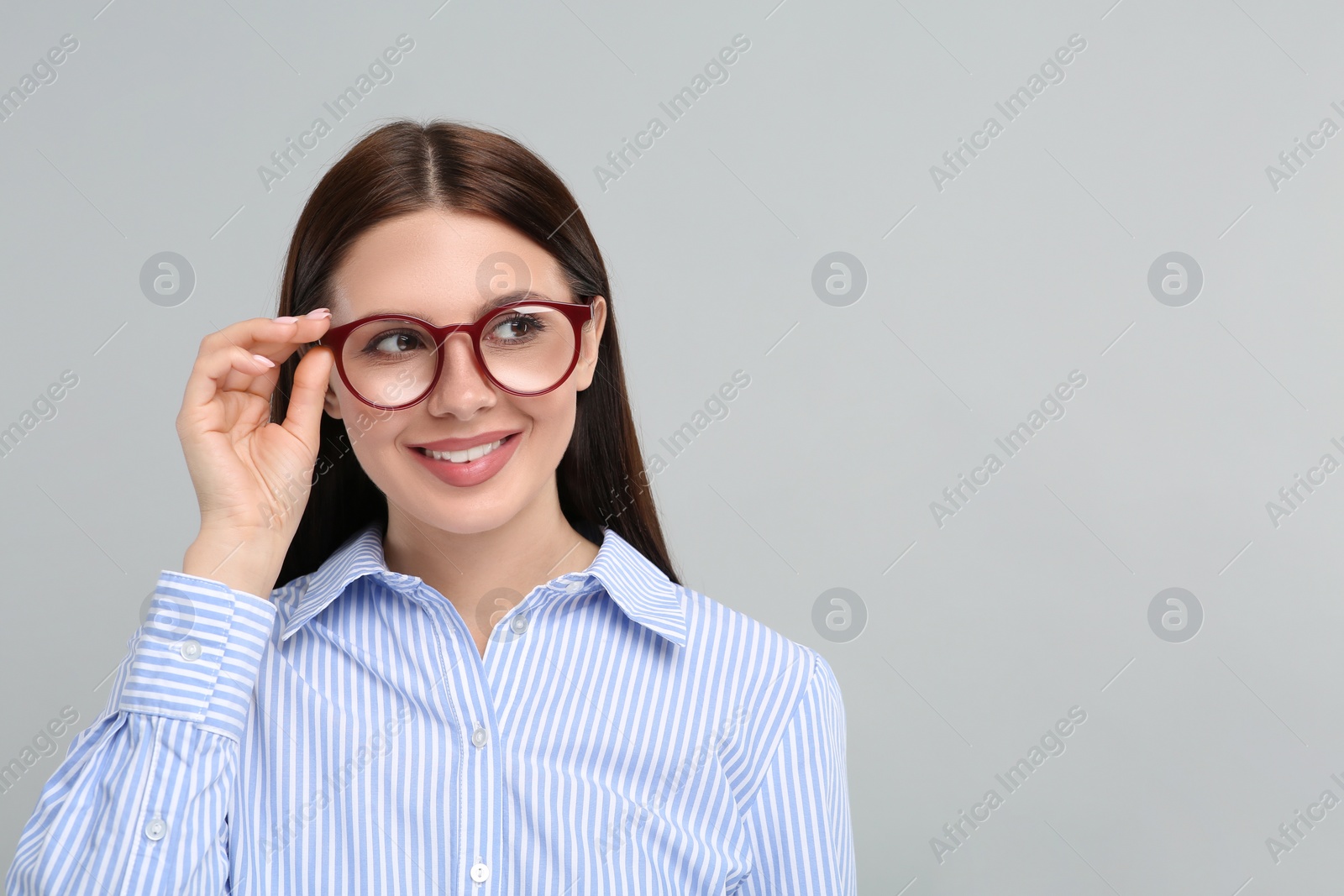 Photo of Smiling woman in stylish eyeglasses on grey background. Space for text