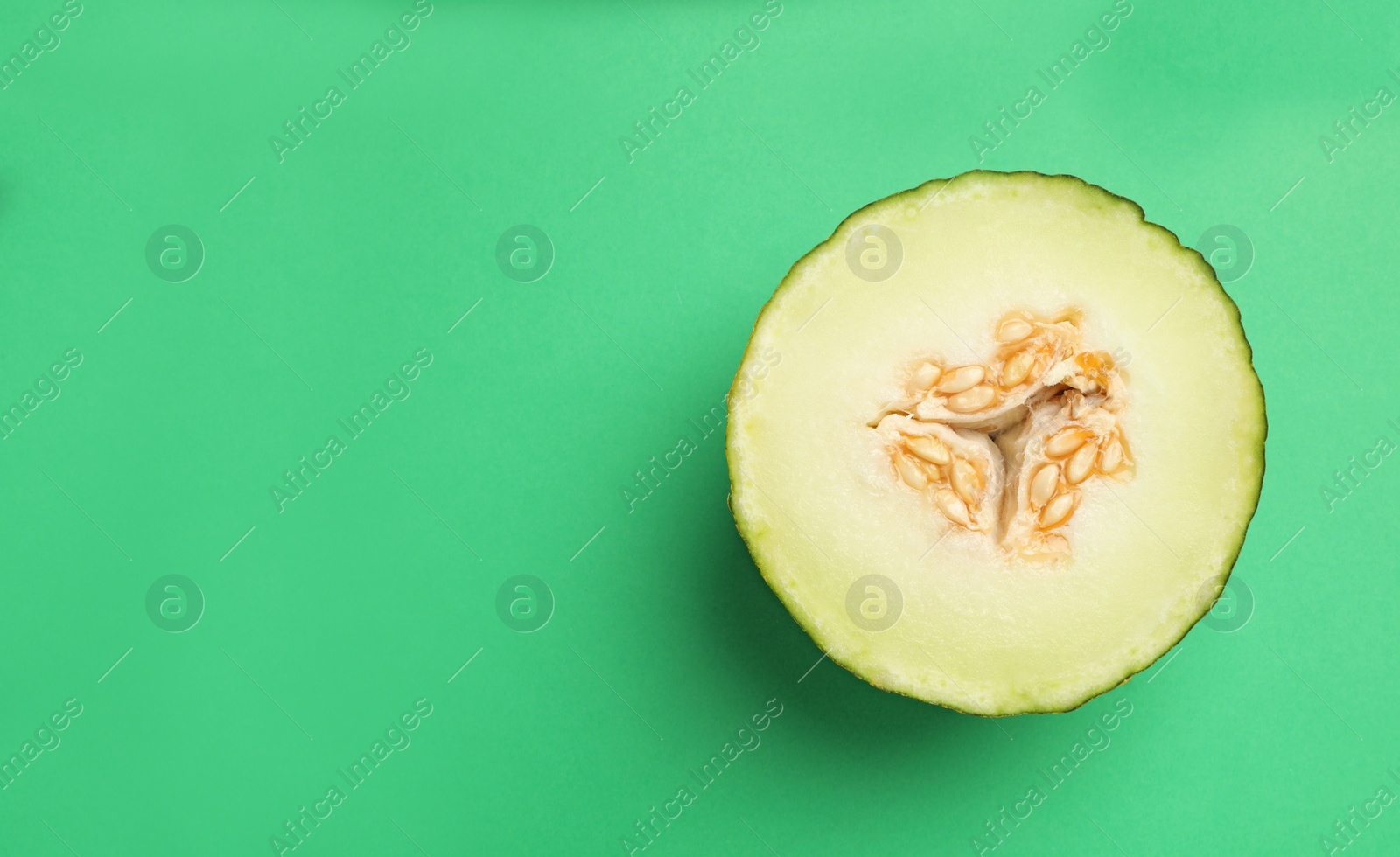 Photo of Half of ripe tasty melon on green background, top view. Space for text