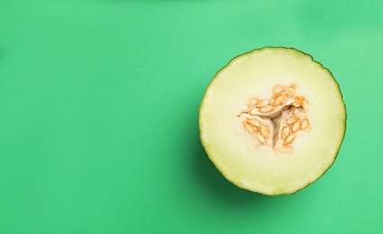 Half of ripe tasty melon on green background, top view. Space for text