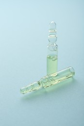 Photo of Glass ampoules with liquid on light blue background