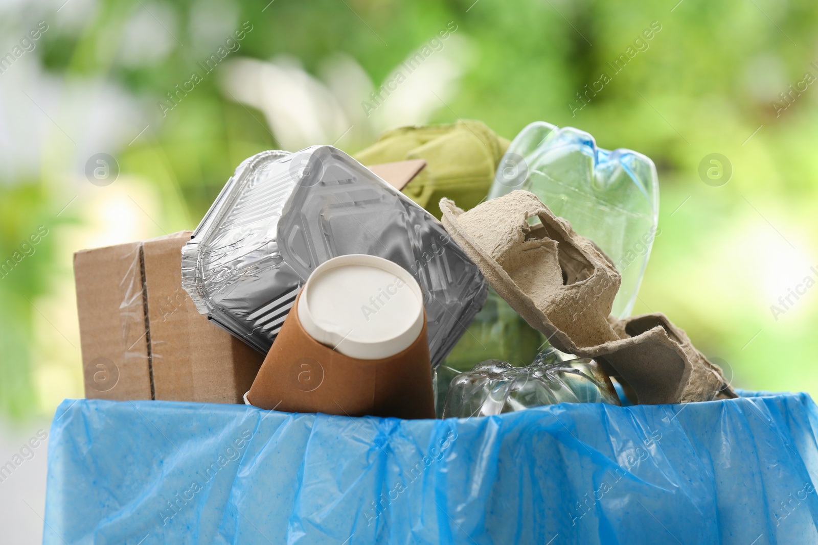 Photo of Trash bin with garbage on blurred background. Recycling problem