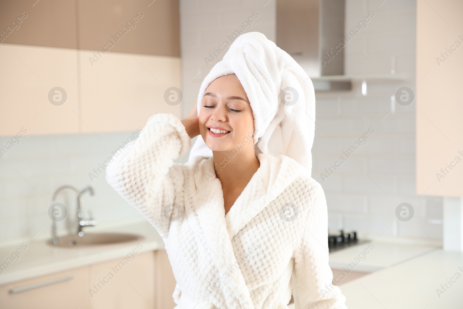 Photo of Beautiful woman with towel on head in kitchen at home