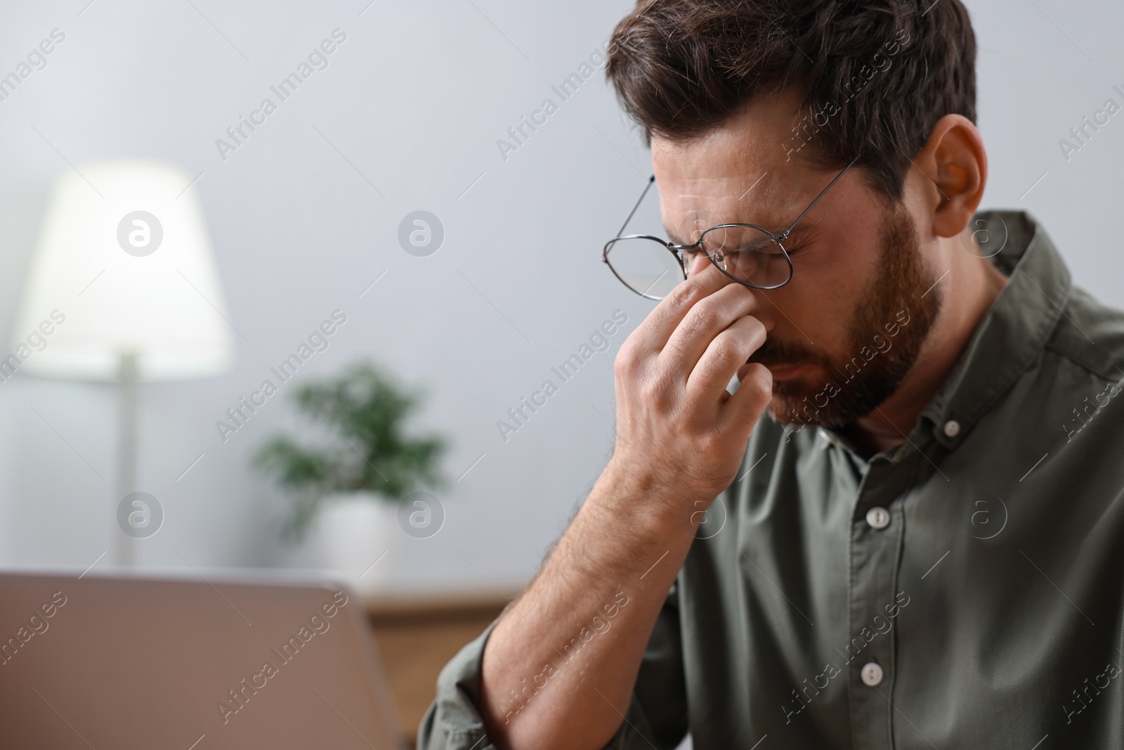 Photo of Tired man suffering from headache indoors. Space for text