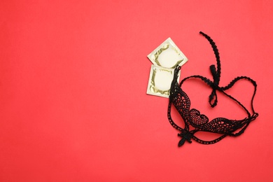 Photo of Lace mask and condoms on red background, top view with space for text. Sex game