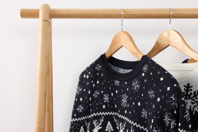 Photo of Rack with Christmas sweaters on white background, closeup