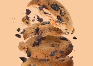 Image of Tasty chocolate chip cookies falling on pale light brown background