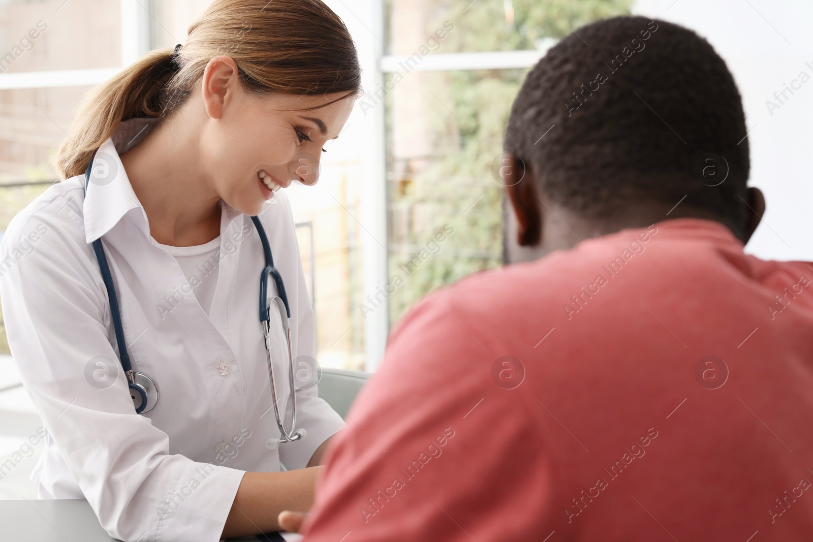 Photo of Young doctor consulting African-American patient in hospital