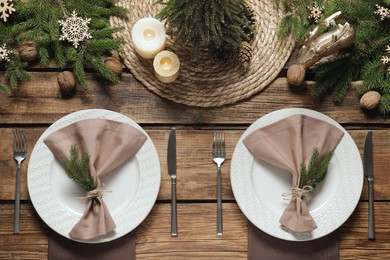 Festive place setting with beautiful dishware, cutlery and fabric napkin for Christmas dinner on wooden table, flat lay